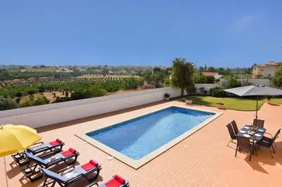 a swimming pool on a patio with chairs and an umbrella at Villa Goia by Villa Plus in Olhos de Água