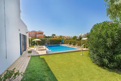 a swimming pool in a yard with chairs and umbrellas at Villa Jorge by Villa Plus in Albufeira