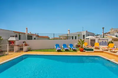 a swimming pool in a yard with chairs at Villa Neptuno Sol by Villa Plus in Albufeira
