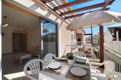 a table with white chairs and an umbrella on a balcony at Apartamento Água Brisa in Albufeira