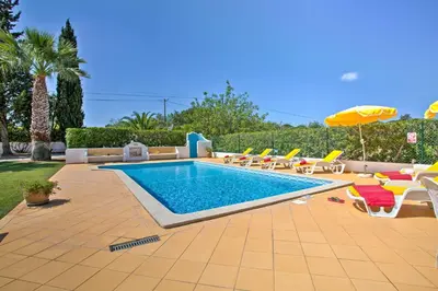 a swimming pool with chairs and an umbrella at Villa Candida by Villa Plus in Vale do Lobo