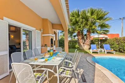 a patio with a table and chairs next to a pool at Villa Casa do Mel by Villa Plus in Loulé