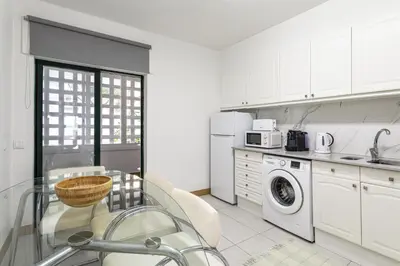 a kitchen with white cabinets and a glass table at Miral 2 - Beach front apartment with pool in Quarteira
