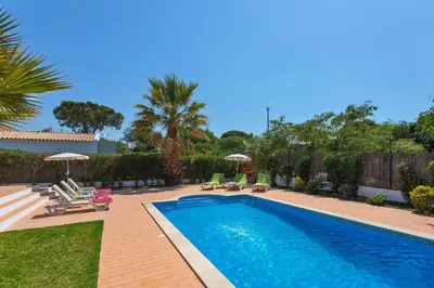 a swimming pool with chairs and umbrellas in a yard at Villa Celia by Villa Plus in Olhos de Água
