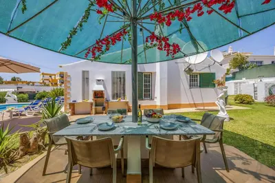 a table with chairs and an umbrella on a patio at Villa Eliza by Villa Plus in Albufeira