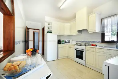 a kitchen with white cabinets and a bowl of fruit on a counter at Villa Medeira by Villa Plus in Albufeira