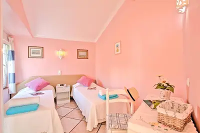 a pink room with two beds and a table at Villa Rocchi by Villa Plus in Albufeira