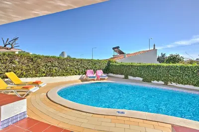 a swimming pool with two lawn chairs and a swimming pool at Villa Vitor by Villa Plus in Albufeira