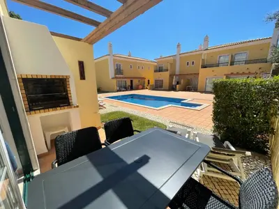 a patio with a table and chairs and a swimming pool at Moradia da Encosta- Vilamoura in Vilamoura