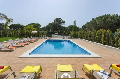 an outdoor swimming pool with chairs and a gazebo at Villa Amora by Villa Plus in Vale do Lobo