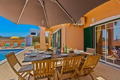 a dining table and chairs with an umbrella on a patio at Villa Bali by Villa Plus in Albufeira