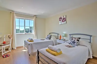 a bedroom with two beds and a window at Villa Beirais by Villa Plus in Vale do Lobo