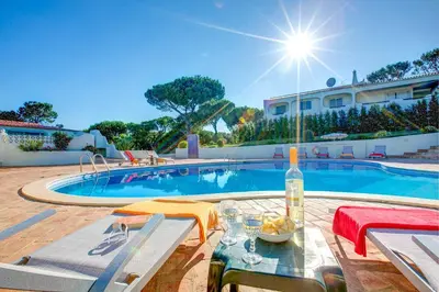 a swimming pool with a table and a bottle of wine at Villa Beirais by Villa Plus in Vale do Lobo