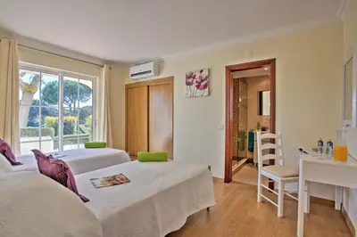a bedroom with two beds and a desk and a window at Villa Beirais by Villa Plus in Vale do Lobo