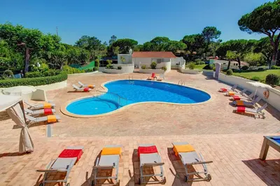 a large swimming pool with chairs and a group at Villa Beirais by Villa Plus in Vale do Lobo
