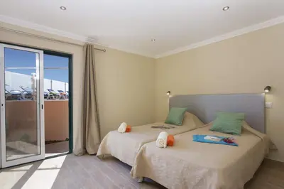 a bedroom with two beds and a sliding glass door at Villa Siroco by Villa Plus in Albufeira