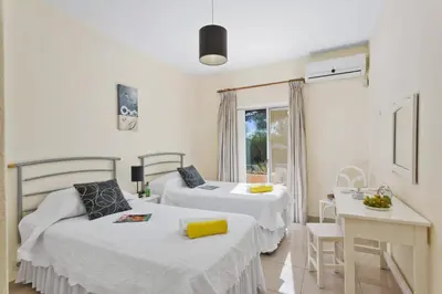 a bedroom with two beds and a table and a window at Villa Uma by Villa Plus in Loulé