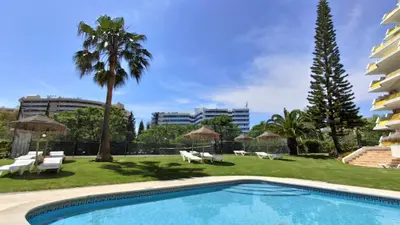 a pool with chairs and umbrellas next to a building at Al-Charb Studio in Quarteira