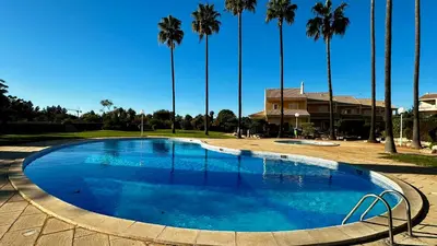 a large blue pool with palm trees in the background at Ellegance by Check-in Portugal in Vilamoura