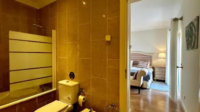 a bathroom with a tub and a toilet and a bedroom at Ellegance by Check-in Portugal in Vilamoura