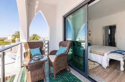 a room with a balcony with a bed and chairs at Riad Matias Galé - Luxury Villa with private pool, AC, free wifi, 5 min from the beach in Guia
