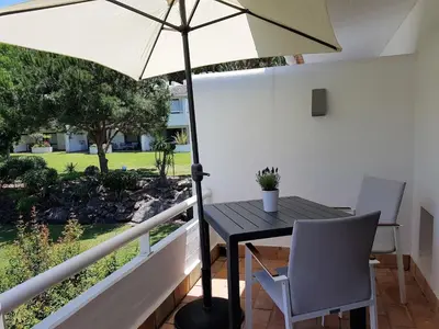 a table and chairs with an umbrella on a balcony at Grey Heron Apartment in Quinta do Lago