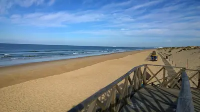 a person standing on a sandy beach near the ocean at Grey Heron Apartment in Quinta do Lago
