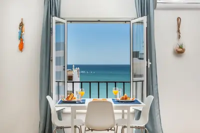 a dining room with a table and chairs and a view of the ocean at Modern ocean view apt 2 min walk to beach in Quarteira