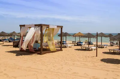 a beach with chairs and umbrellas and the ocean at Modern ocean view apt 2 min walk to beach in Quarteira