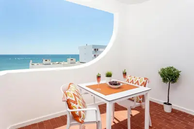 a white table and chairs on a balcony with the ocean at Modern ocean view apt 2 min walk to beach in Quarteira