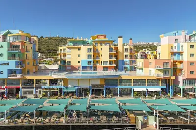 a group of buildings with tables and umbrellas at Marina Breeze Apartment with Pool - 900m from the Beach in Albufeira