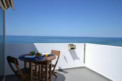 a table and chairs on a balcony with the ocean at Ria Beach Studio in Faro