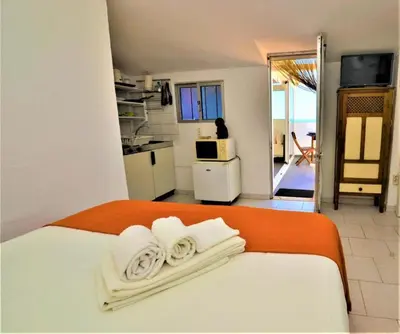 a bed with an orange blanket and two towels on it at Ria Beach Studio in Faro