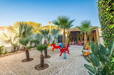 a courtyard with palm trees and plastic horses in front of a building at Villa Galé Sun - Luxury, 5bed with free wifi, AC, private pool, 5 min from the beach in Guia