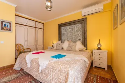 a bedroom with a bed with yellow walls and a window at Riad Serpa Galé - Luxury, private pool, AC, wifi, 5 min from the beach in Guia