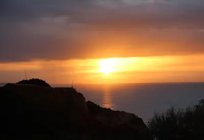 a sunset over the ocean with the sun setting at Ocean and pool in Olhos de Água