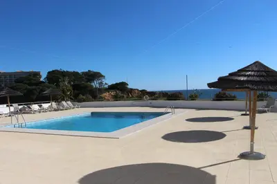 a swimming pool with an umbrella on a patio at Ocean and pool in Olhos de Água