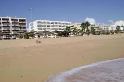 a sandy beach with buildings in the background at Quarteira 1-Bed Sleeps 4 Parking 1 min to Beach in Quarteira