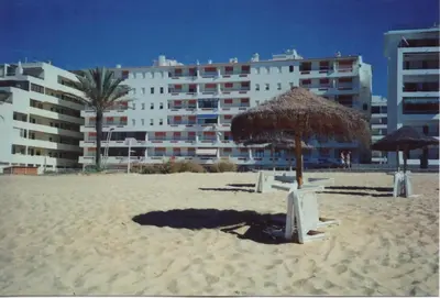 a beach with two chairs and an umbrella and a building at Quarteira 1-Bed Sleeps 4 Parking 1 min to Beach in Quarteira