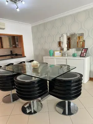 a dining room with a glass table and black stools at V3 Vitória Boulevard in Vilamoura