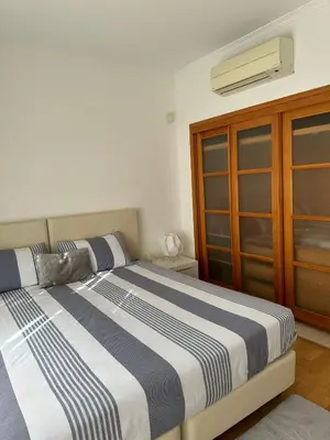a bedroom with a bed and a wooden cabinet at V3 Vitória Boulevard in Vilamoura