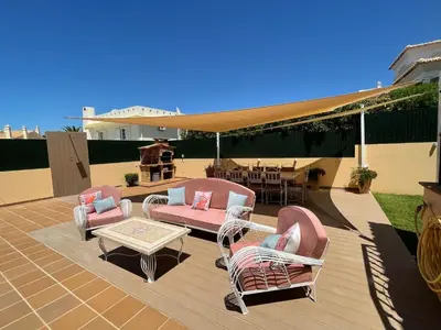 a patio with wicker chairs and a table and a grill at Villa Mar Azul in Albufeira