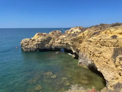 a cave in the ocean with people swimming in the water at Villa Mar Azul in Albufeira