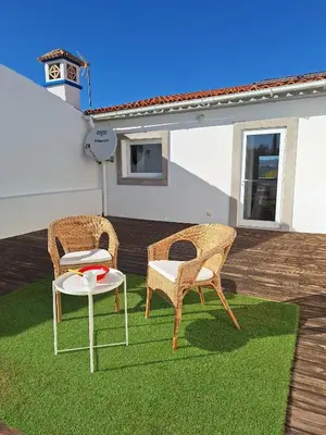 two wicker chairs and a table on a lawn at Casa Bravo in Querença