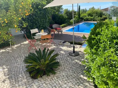 a patio with a table and an umbrella next to a pool at Casa Bravo in Querença