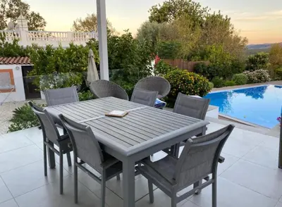 a table and chairs on a patio with a pool at Casa Bravo in Querença