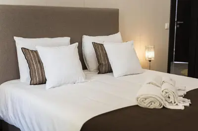 a large white bed with pillows and towels on it at Marina Luxor - Vilamoura in Quarteira