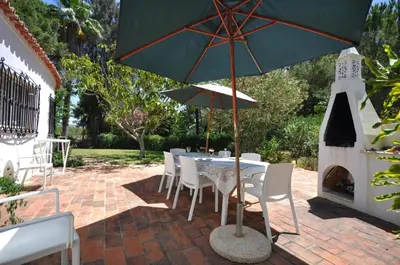 a table and chairs with an umbrella on a patio at Fantastic outdoor area, private pool, Tennis Court Golf Practice Facility in Faro