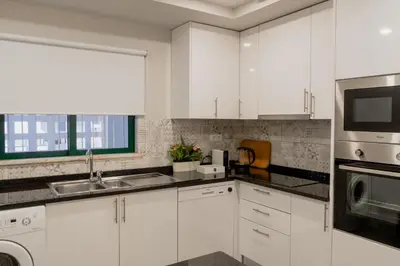 a white kitchen with a sink and a microwave at Comfort Zone beach apartment in Quarteira