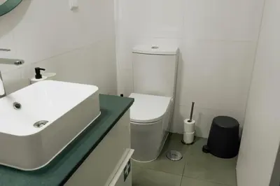 a white bathroom with a sink and a toilet at Comfort Zone beach apartment in Quarteira